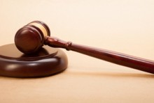 A wooden gavel and soundboard on a light brown background.