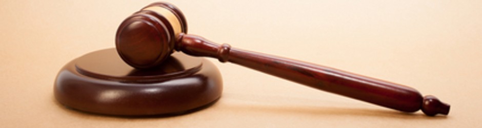 A wooden gavel and soundboard on a light brown background.